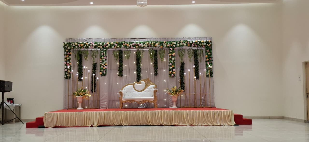 Floral stage backdrop and sofa setup inside Raj Rajeshwari AC Banquet Hall, Jule Solapur